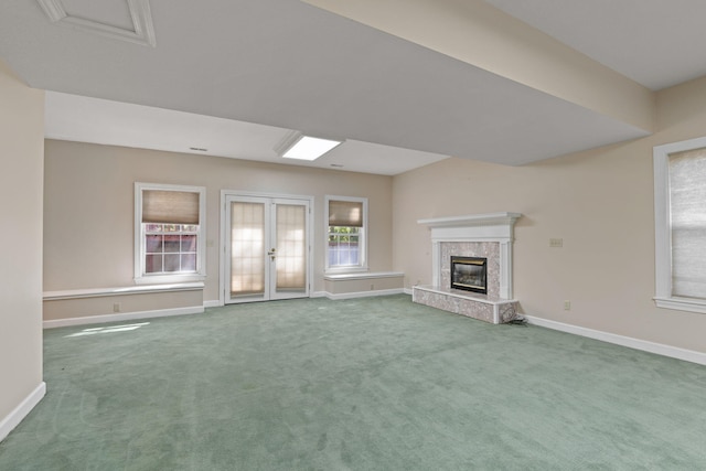 unfurnished living room featuring french doors, carpet flooring, baseboards, and a premium fireplace