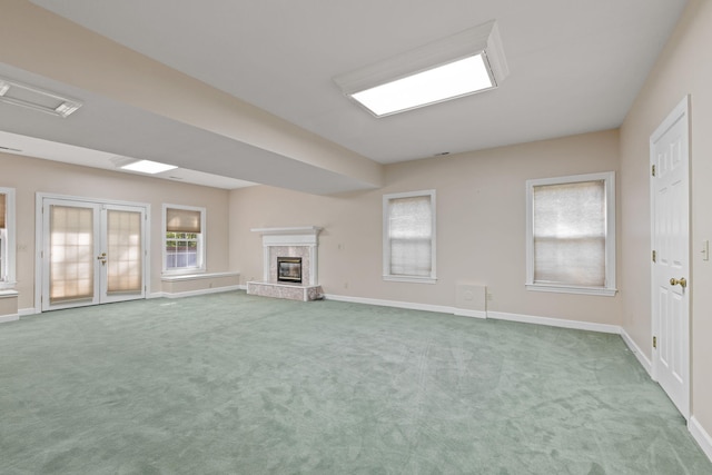 unfurnished living room with french doors, a premium fireplace, carpet, and baseboards