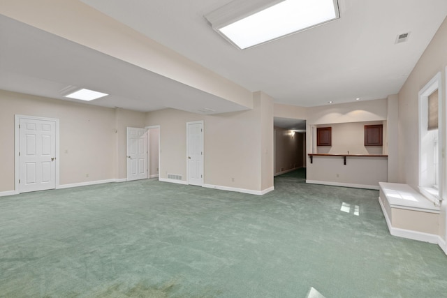 unfurnished living room featuring carpet, visible vents, and baseboards