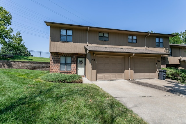 view of property featuring concrete driveway, an attached garage, brick siding, and a front lawn