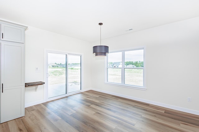 unfurnished dining area with light wood-style flooring, baseboards, and a wealth of natural light