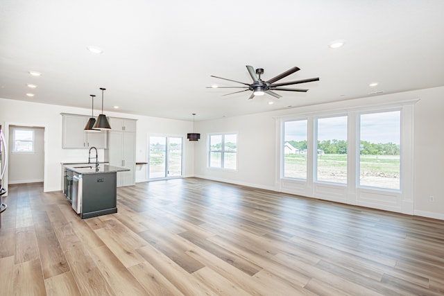 unfurnished living room with sink, light hardwood / wood-style flooring, and ceiling fan