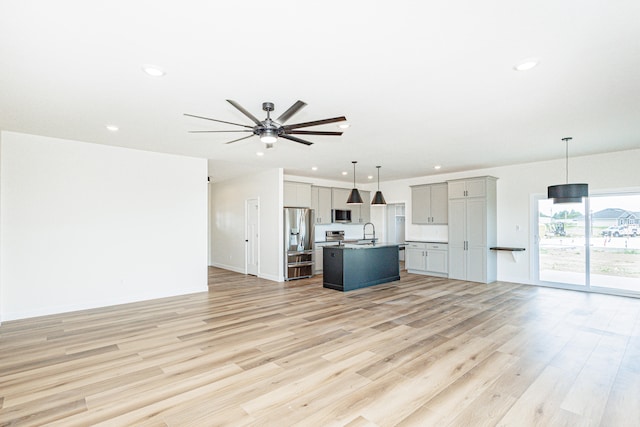 unfurnished living room with ceiling fan, light wood-type flooring, and sink