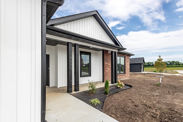 property entrance with a porch, board and batten siding, and brick siding