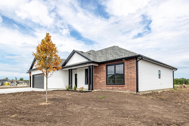 view of front of house with a shingled roof, concrete driveway, brick siding, and an attached garage