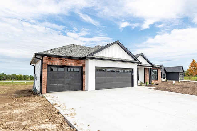 modern farmhouse style home featuring a garage, driveway, brick siding, and a shingled roof