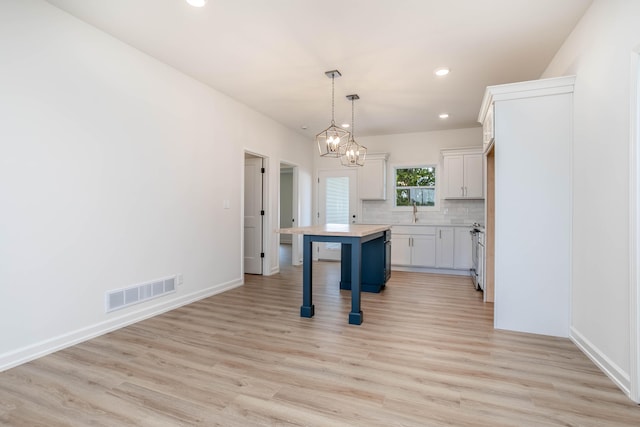 kitchen with backsplash, a center island, light hardwood / wood-style flooring, white cabinetry, and a breakfast bar area