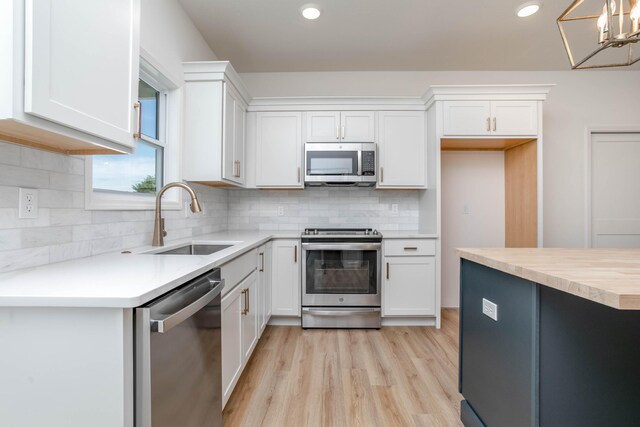 kitchen featuring sink, white cabinetry, appliances with stainless steel finishes, and light hardwood / wood-style floors