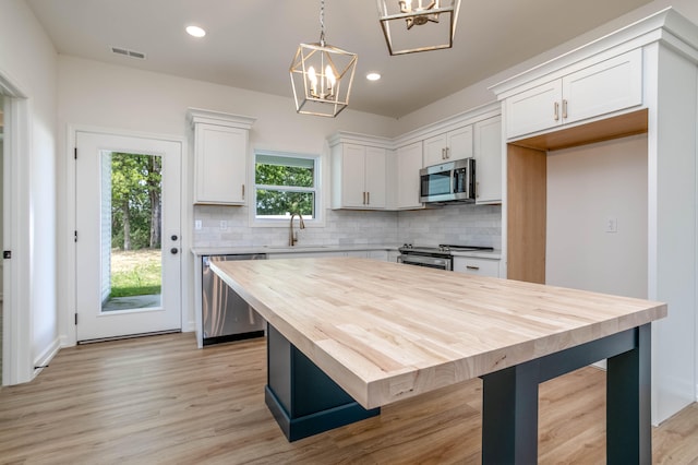 kitchen with backsplash, stainless steel appliances, light hardwood / wood-style floors, and white cabinetry