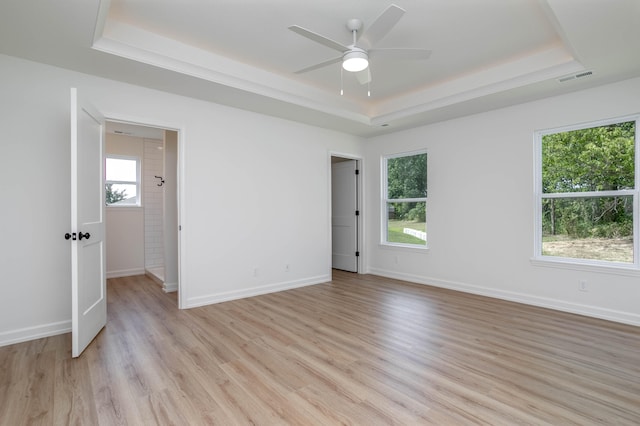 unfurnished bedroom with ceiling fan, a tray ceiling, and light hardwood / wood-style floors