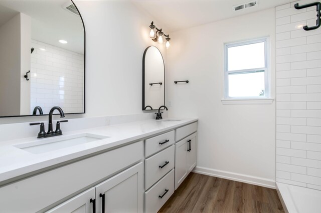 bathroom featuring hardwood / wood-style floors, a tile shower, and vanity