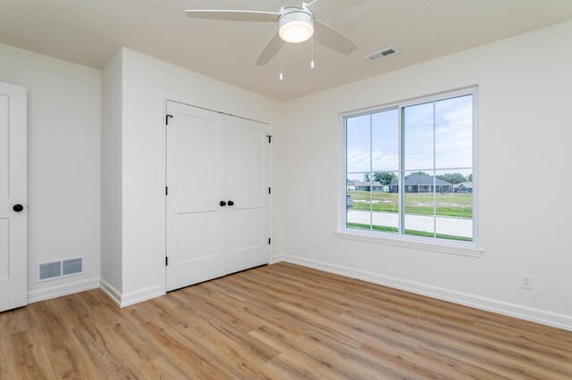 unfurnished bedroom featuring ceiling fan, light wood-type flooring, and a closet