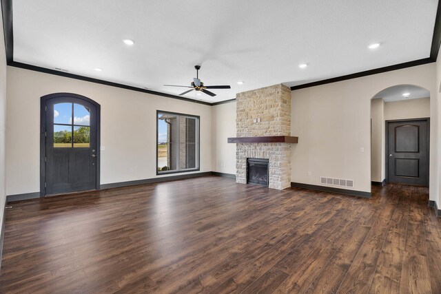 unfurnished living room featuring ceiling fan, a fireplace, dark hardwood / wood-style flooring, and ornamental molding