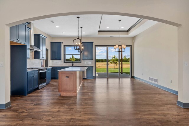 kitchen featuring backsplash, an inviting chandelier, dark hardwood / wood-style flooring, stainless steel range, and a kitchen island