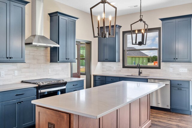 kitchen with a center island, decorative light fixtures, appliances with stainless steel finishes, sink, and wall chimney exhaust hood