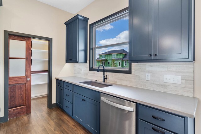 kitchen featuring dishwasher, dark hardwood / wood-style flooring, sink, blue cabinets, and tasteful backsplash