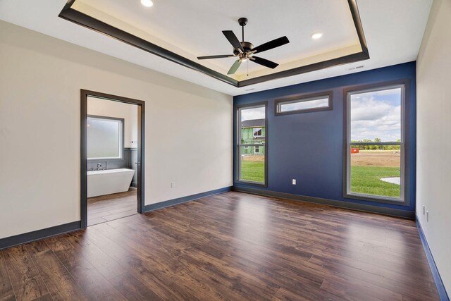 empty room featuring ceiling fan, dark hardwood / wood-style floors, and a raised ceiling