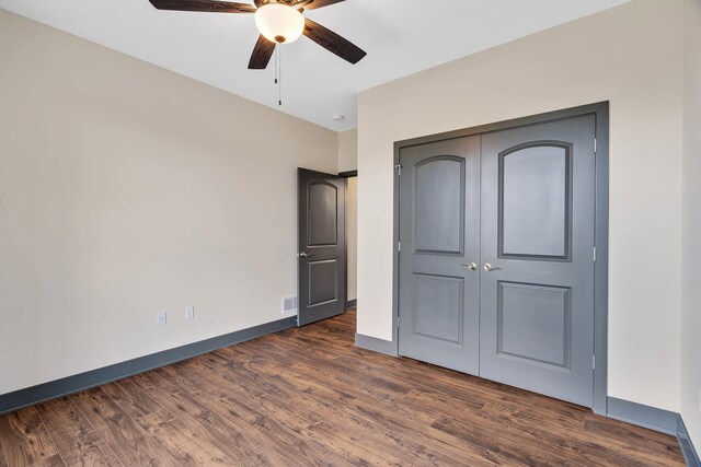 unfurnished bedroom with dark wood-type flooring, ceiling fan, and a closet