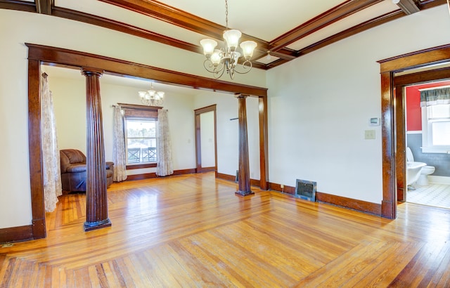 empty room featuring an inviting chandelier, beam ceiling, light hardwood / wood-style floors, and ornate columns