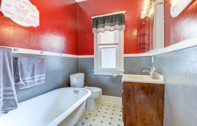 bathroom featuring tile walls, a bathtub, vanity, and toilet