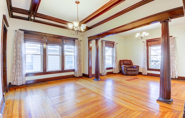 unfurnished room featuring a notable chandelier, a wealth of natural light, and ornate columns