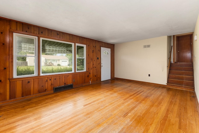 unfurnished room featuring light hardwood / wood-style flooring and wooden walls