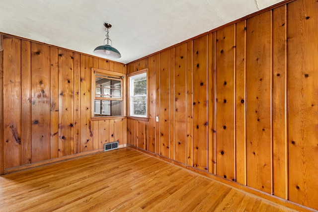 spare room featuring wood walls and hardwood / wood-style floors