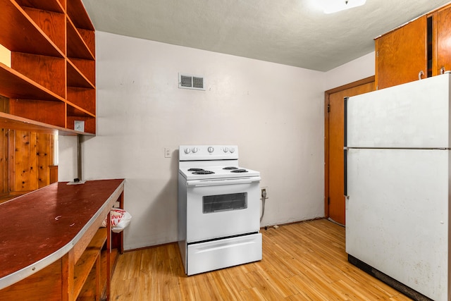 kitchen featuring a textured ceiling, white appliances, and light hardwood / wood-style floors