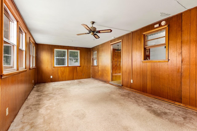 spare room featuring ceiling fan, wooden walls, and carpet