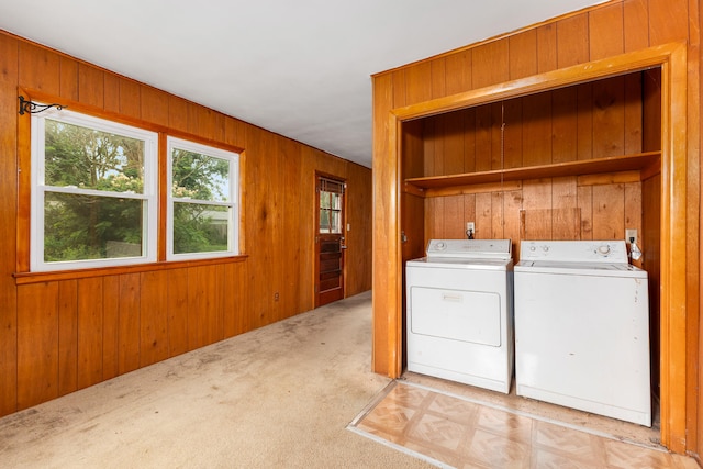 laundry room with wood walls, light colored carpet, and washer and clothes dryer