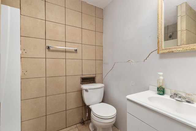 bathroom with a textured ceiling, vanity, tile walls, toilet, and tile patterned floors