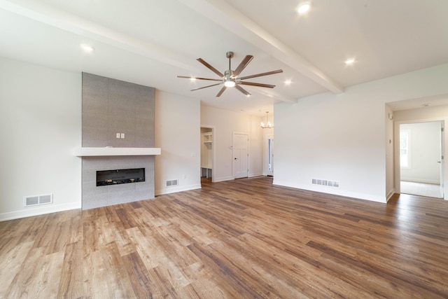 unfurnished living room with beam ceiling, light hardwood / wood-style floors, a tile fireplace, and ceiling fan