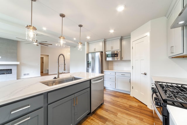 kitchen featuring decorative light fixtures, appliances with stainless steel finishes, sink, and gray cabinetry