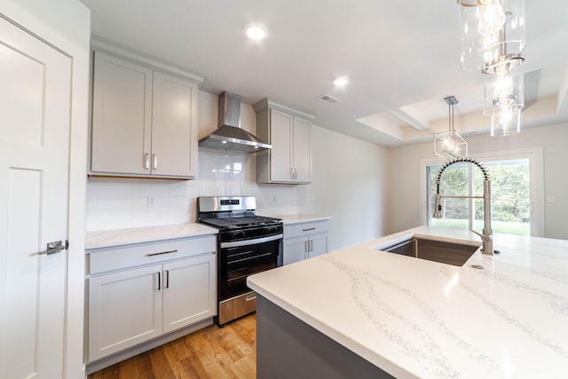 kitchen featuring gas stove, gray cabinetry, wall chimney exhaust hood, and sink