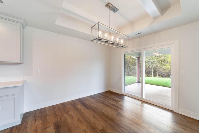 unfurnished dining area with a tray ceiling and dark wood-type flooring