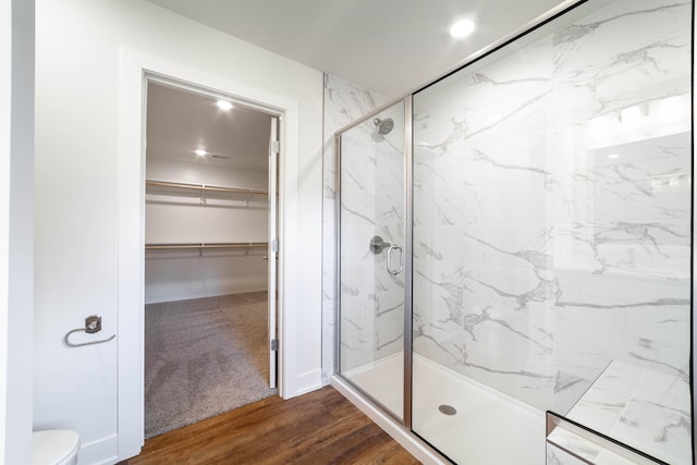 bathroom with hardwood / wood-style floors, an enclosed shower, and toilet