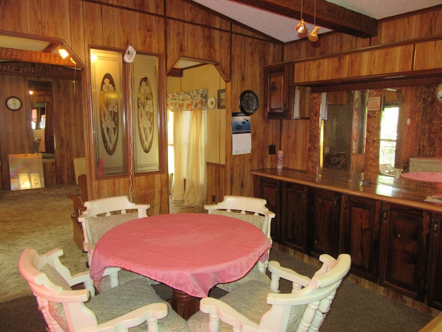 dining space featuring carpet flooring, wood walls, and vaulted ceiling with beams