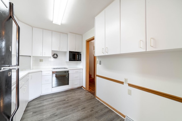 kitchen featuring black appliances, backsplash, light hardwood / wood-style floors, and white cabinetry