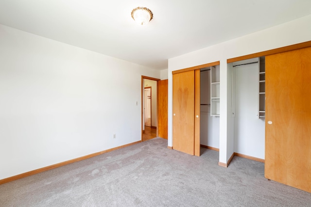 unfurnished bedroom with light carpet and multiple closets