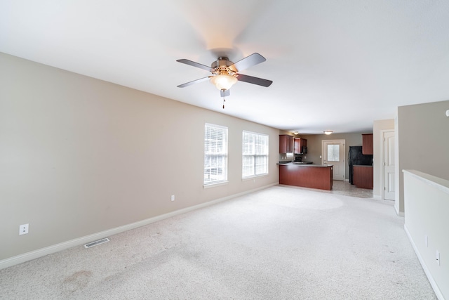 unfurnished living room featuring ceiling fan and light colored carpet