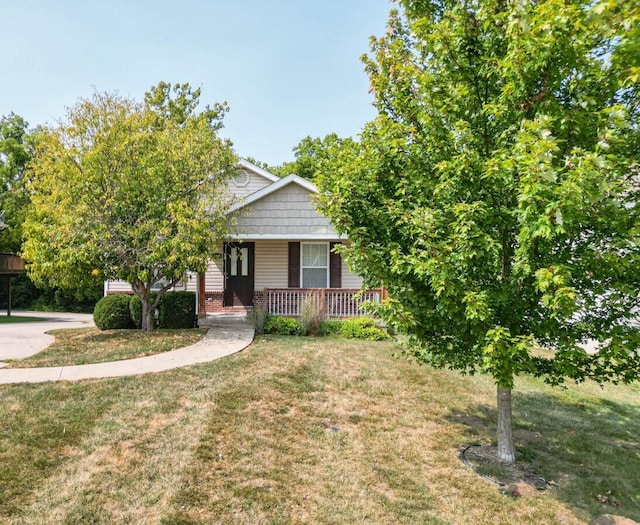 view of property hidden behind natural elements featuring a front yard and covered porch