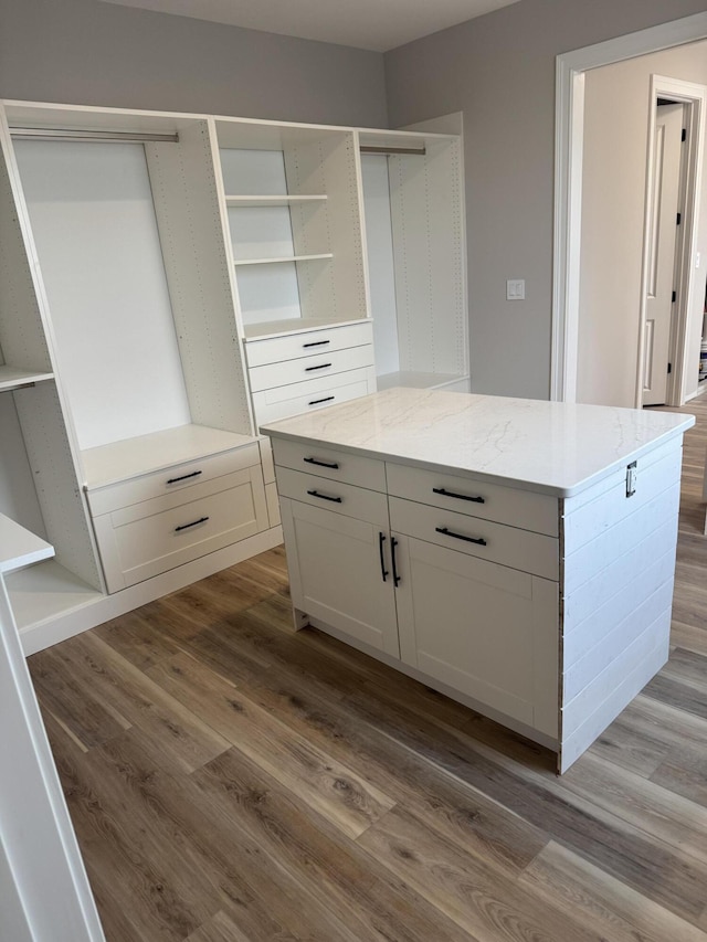 kitchen with white cabinetry, hardwood / wood-style floors, and light stone counters