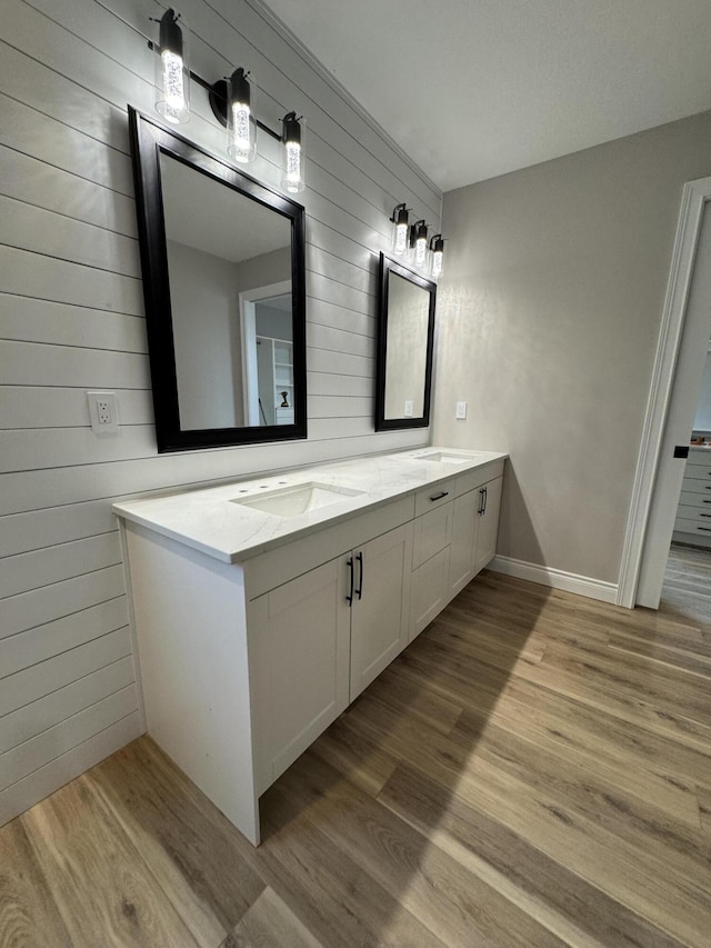 bathroom with wood-type flooring, vanity, and wood walls