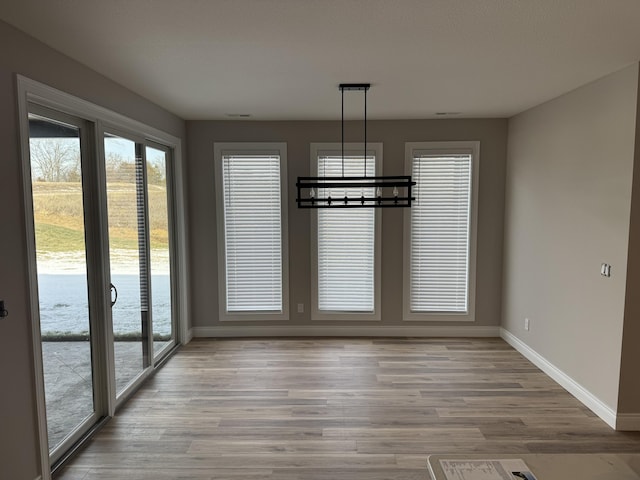 unfurnished dining area featuring hardwood / wood-style flooring and a notable chandelier