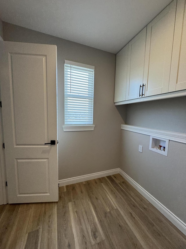 washroom with washer hookup, light hardwood / wood-style floors, and cabinets