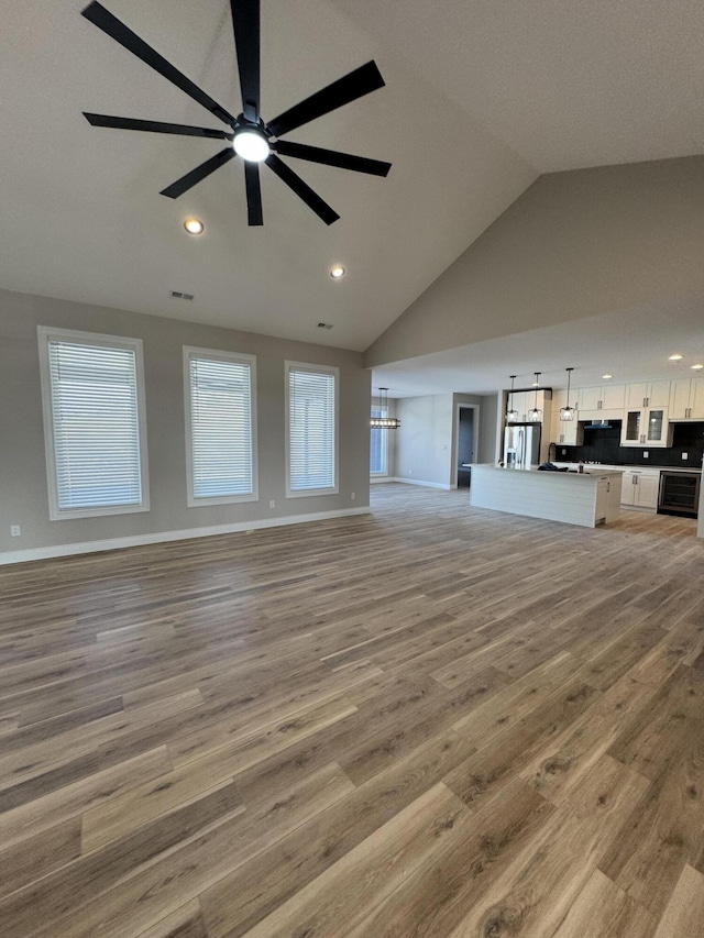 unfurnished living room with vaulted ceiling, ceiling fan, and light hardwood / wood-style flooring