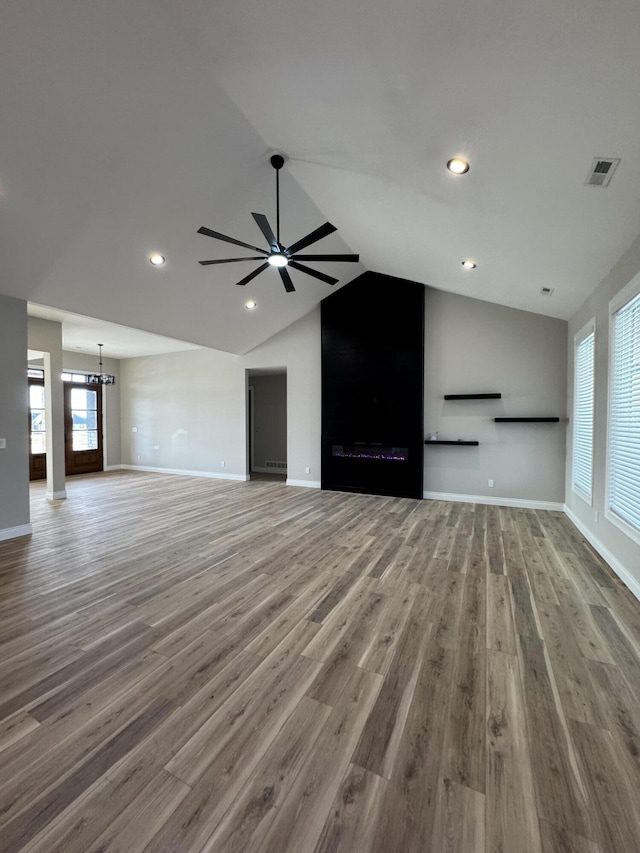 unfurnished living room featuring lofted ceiling, wood-type flooring, and ceiling fan with notable chandelier