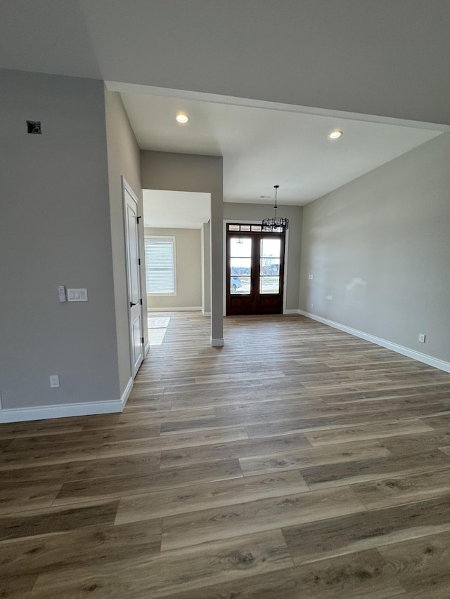 unfurnished room with hardwood / wood-style flooring, a notable chandelier, and french doors