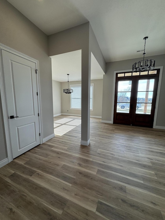 entrance foyer featuring wood-type flooring, french doors, and a chandelier