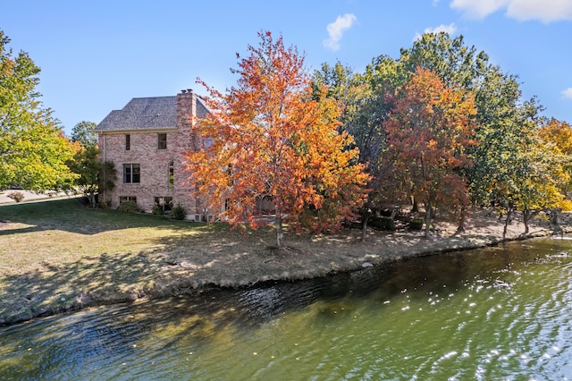 rear view of house with a water view and a yard